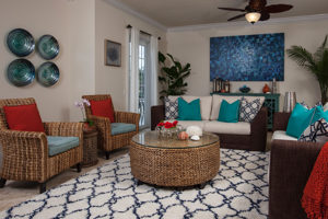 A well-decorated living room with two chairs and two couches uses turquoise, blue, and red colored items to create a comfortable space.