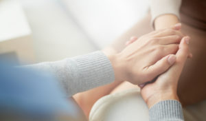 Two women hold hands to comfort each other