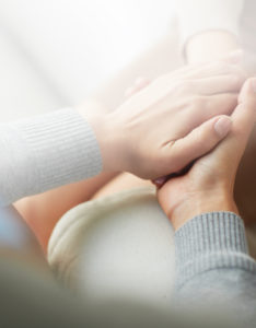 Two women hold hands to comfort each other