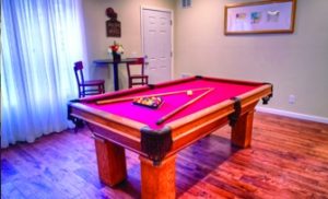 A room contains a red pool table and a wooden table with bar chairs.