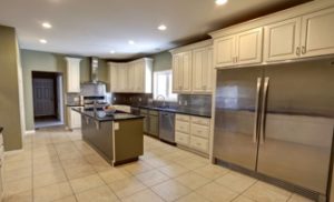 A large kitchen contains white cupboards, granite counters, and stainless steel appliances.