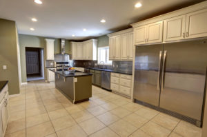 A large kitchen contains white cupboards, granite counters, and stainless steel appliances.