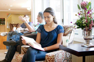 A girl sitting on a couch calmly reading a book